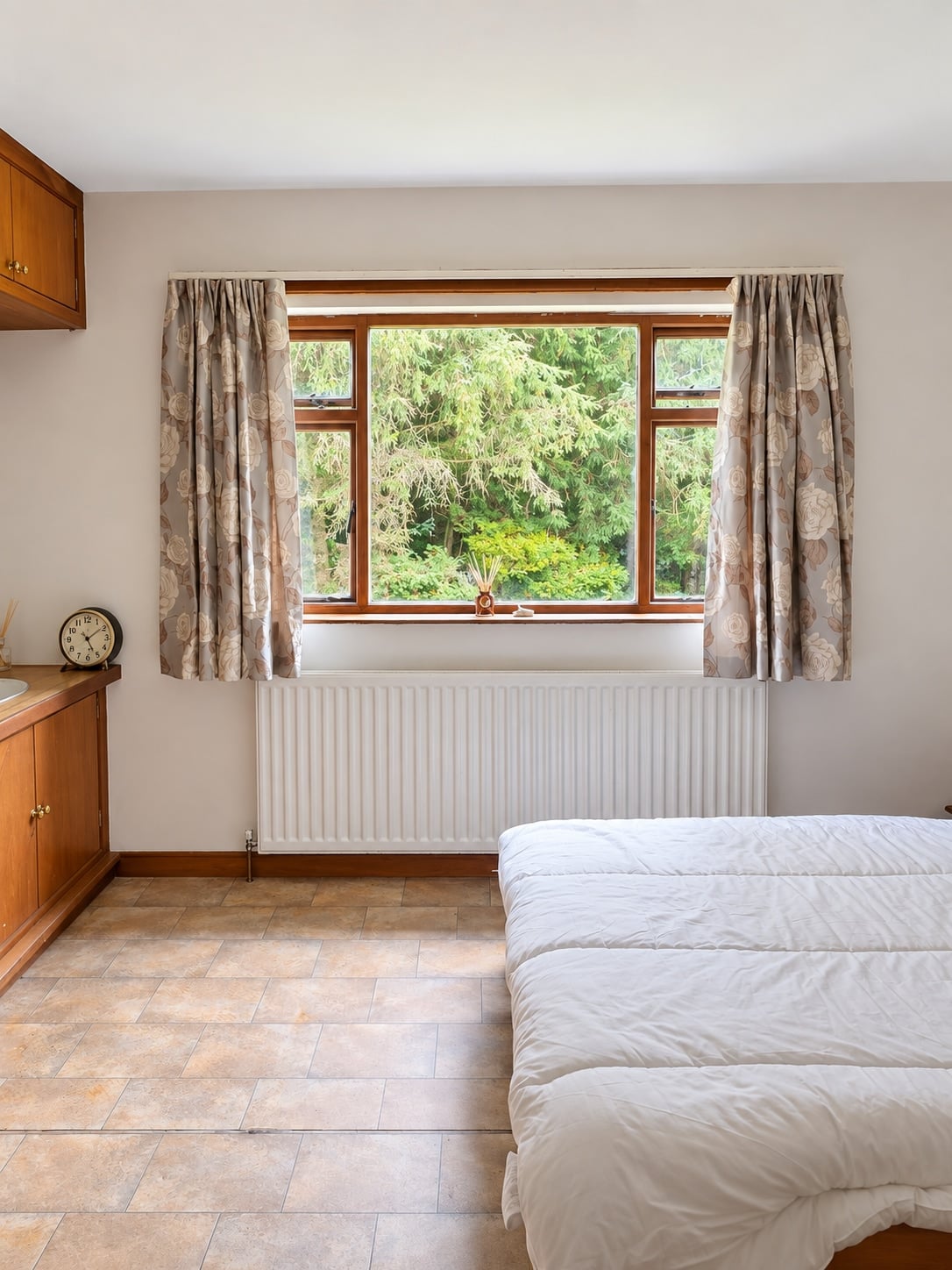 Bedroom with a large window, fitted cupboards and tiled floor