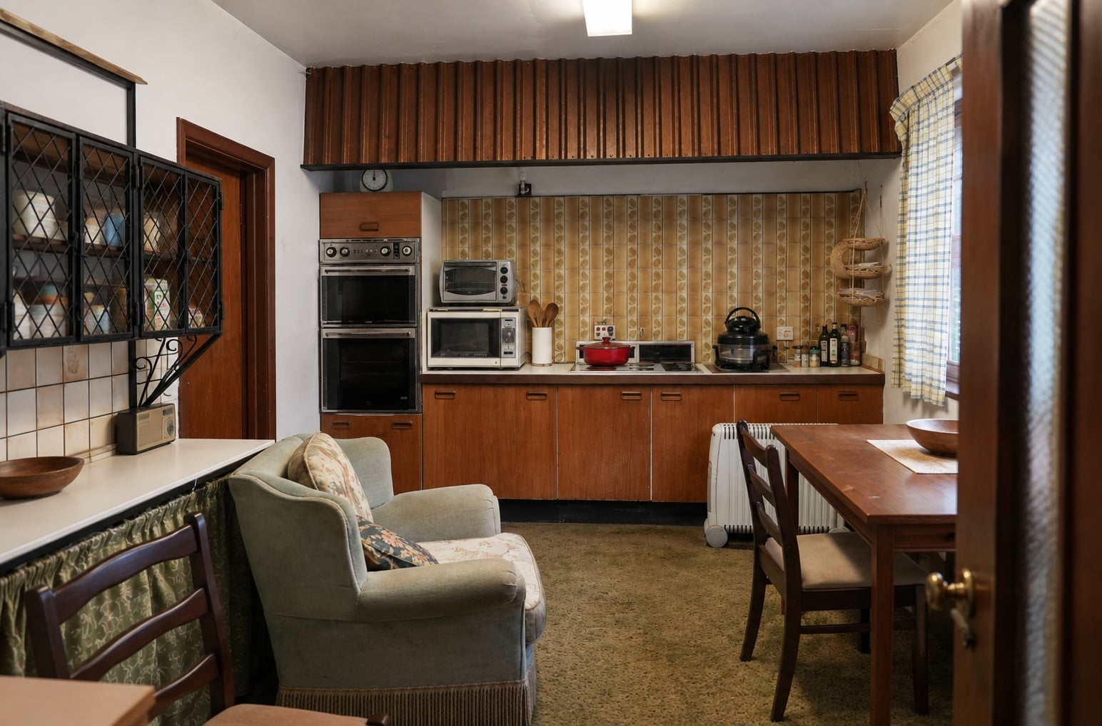 Kitchen showing wooden cabinets, ovens, cooking area and seating