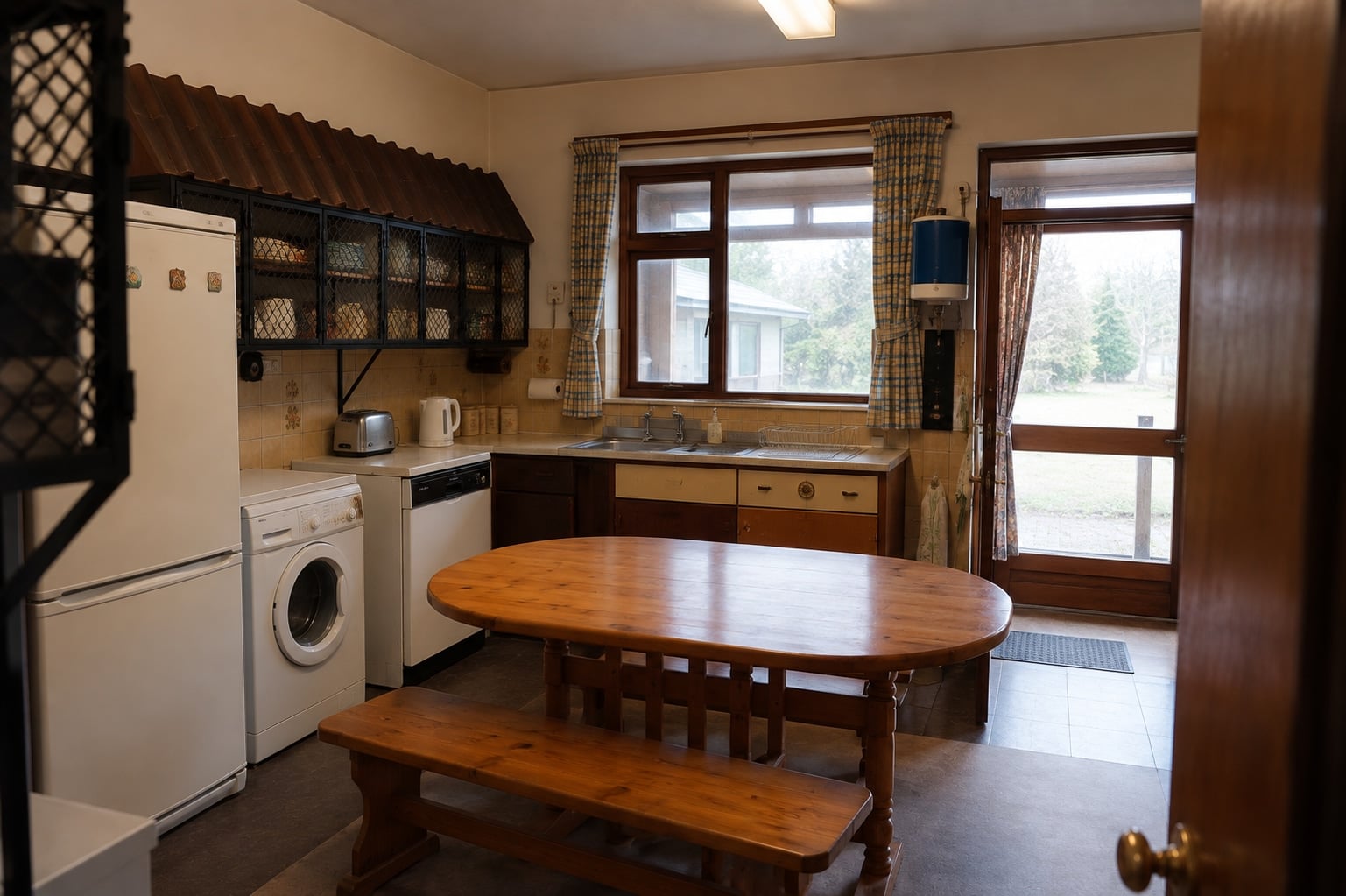 Kitchen with a wooden dining table, sink beneath the window and a door to the porch