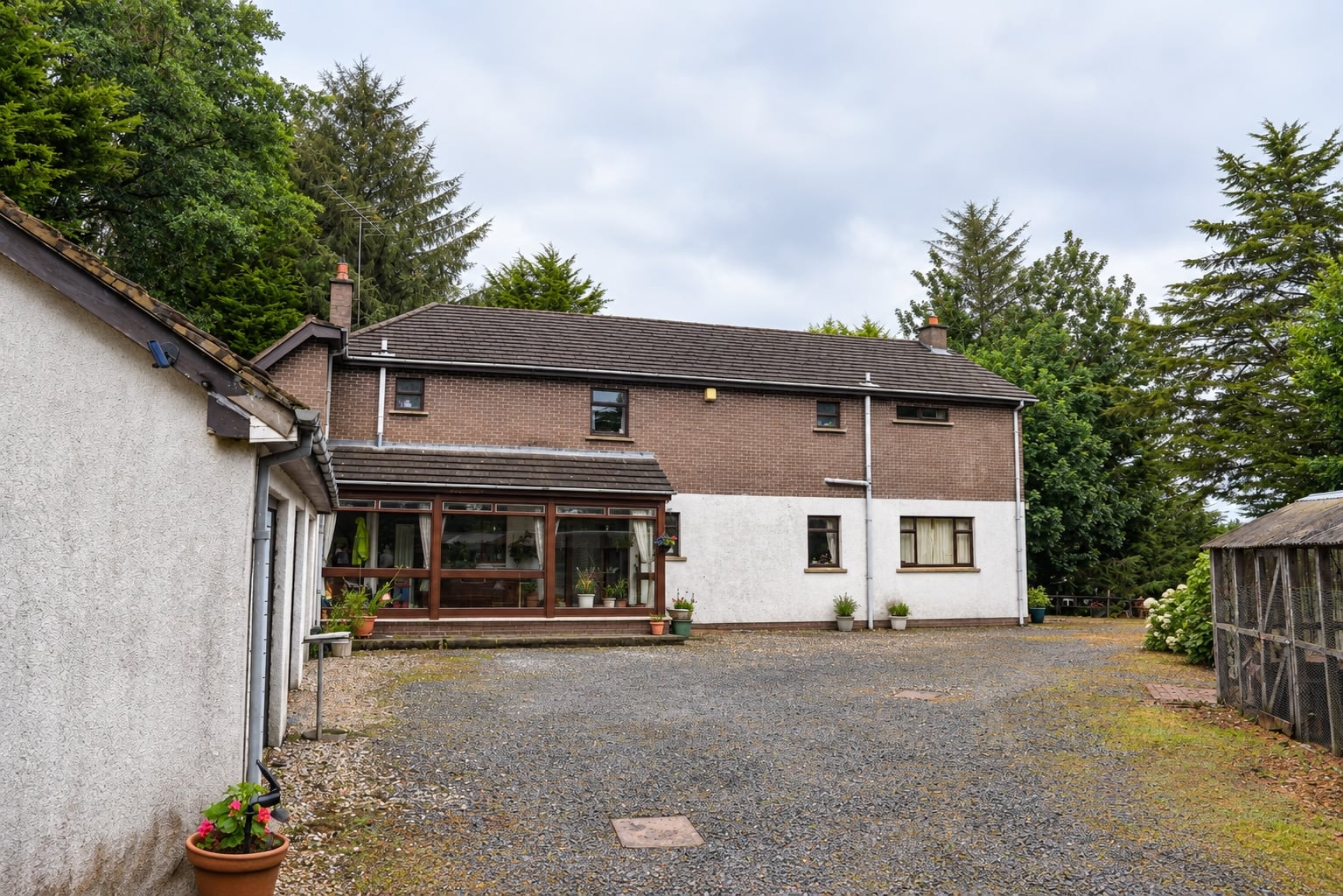 Exterior of the house with a glazed porch and gravel courtyard